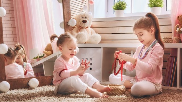 Cute little children are playing together. Happy girls at home. Funny lovely sisters are having fun in kids room.