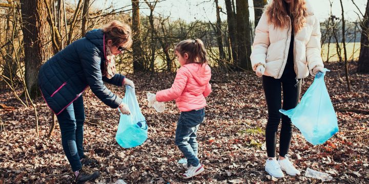 Family cleaning up a forest. Volunteers picking plastic waste to bags. Concept of plastic pollution and too many plastic waste. Environmental issue. Environmental damage. Responsibilitiy for environment. Real people, authentic situations