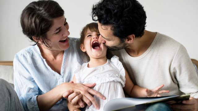 Happy parents laughing together with daughter