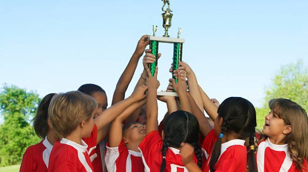 Group of children holding trophy above heads