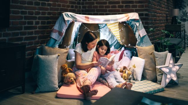 Mother and daughter having a pajama party reading a book