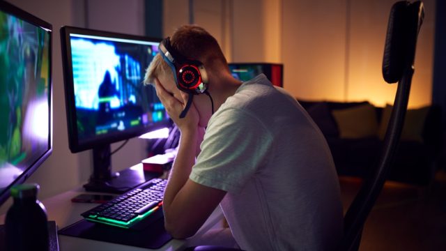 Stressed Teenage Boy Being Bullied Online Whilst Gaming At Home
